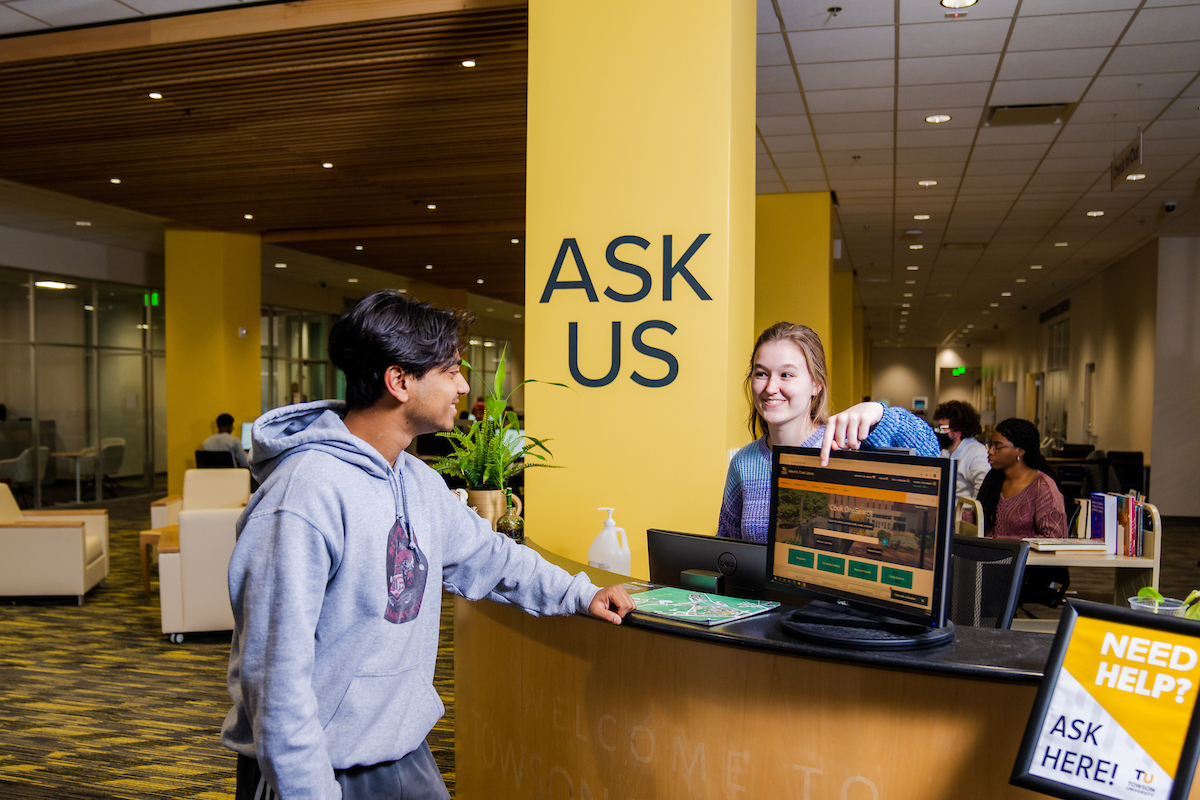 Two people standing and chatting at the 'Ask Us' desk