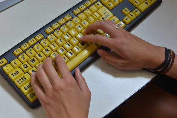 Hands typing on a high contrast keyboard