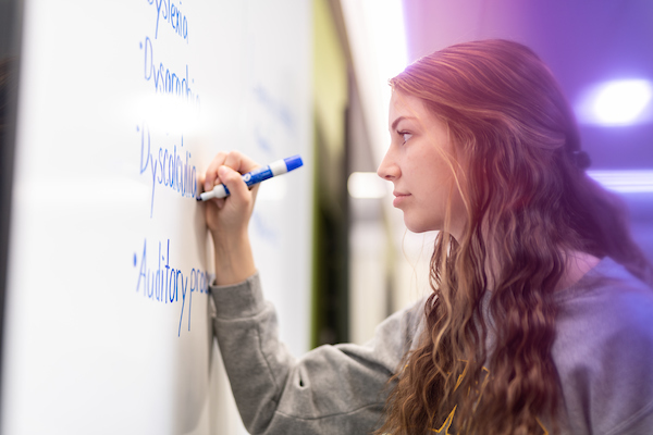 A young woman uses a whiteboard