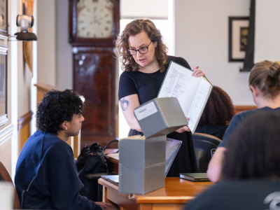 A librarian holding a book and talking to a student