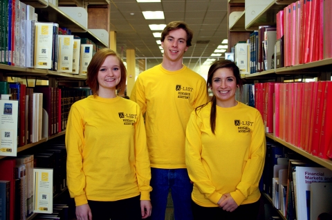 Former A-LIST students smile among the library bookcases